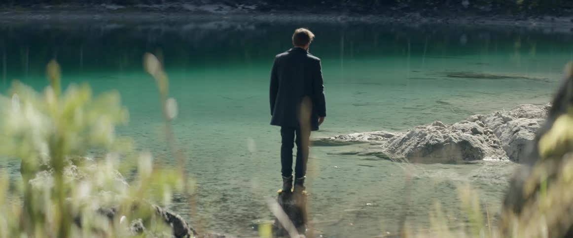 A man stands at the edge of the water
