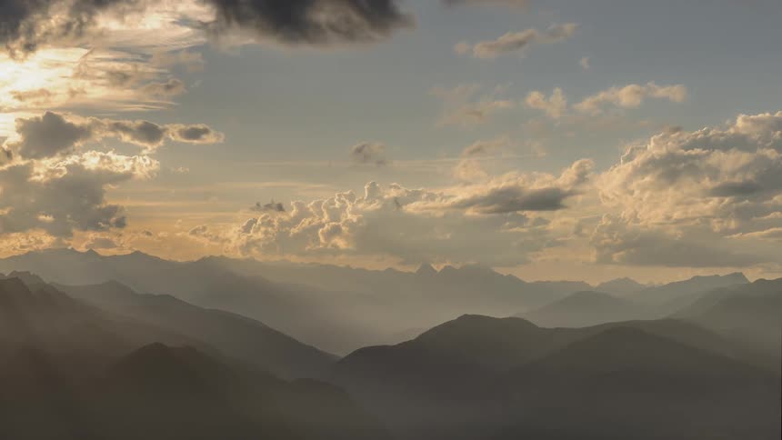 Sun breaking through clouds over mountains