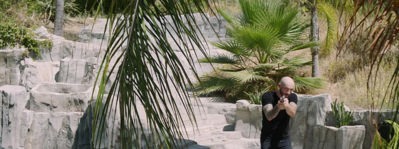 A man walks down the stone steps with a gun