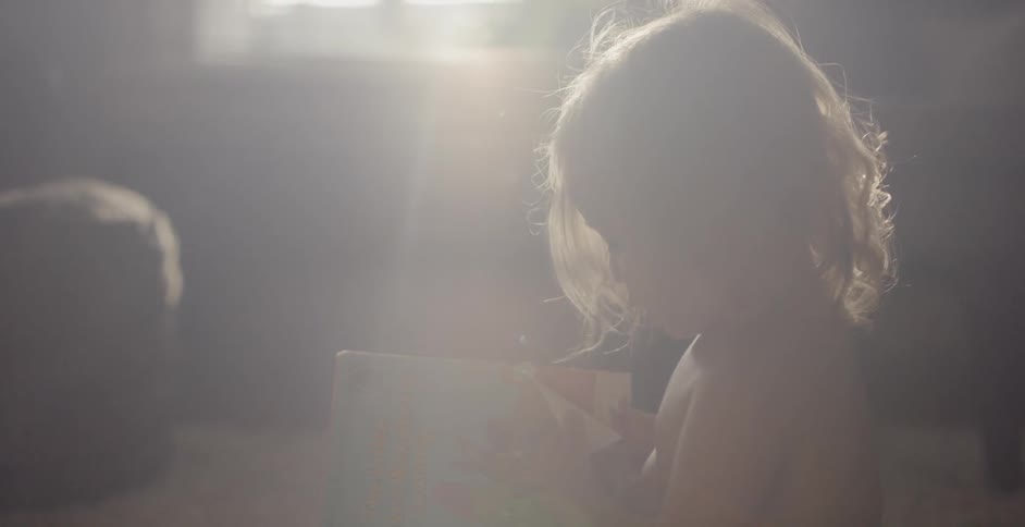 A child plays with a book in the sunshine