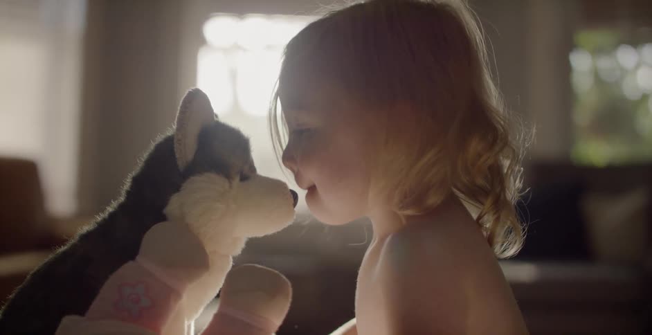A small baby kisses a stuffed animal dog