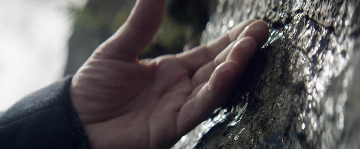 A man rubs a wet stone wall