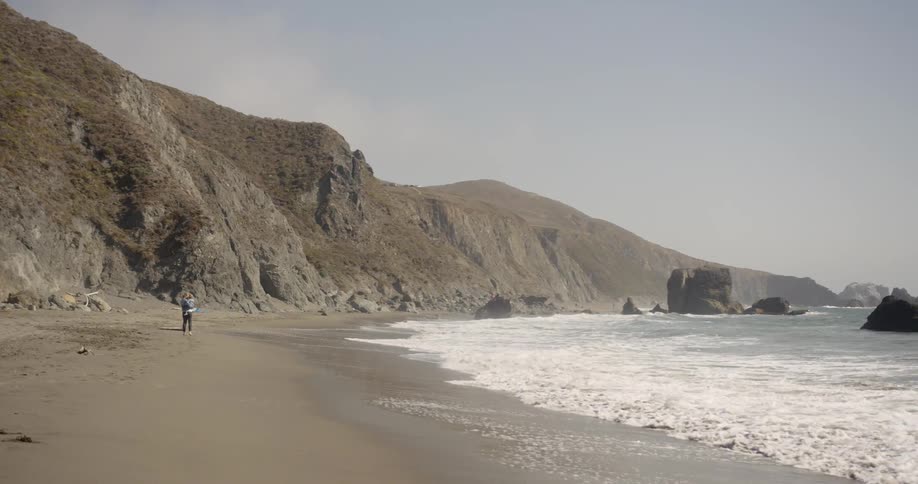 A person stands on the shore as waves come ashore