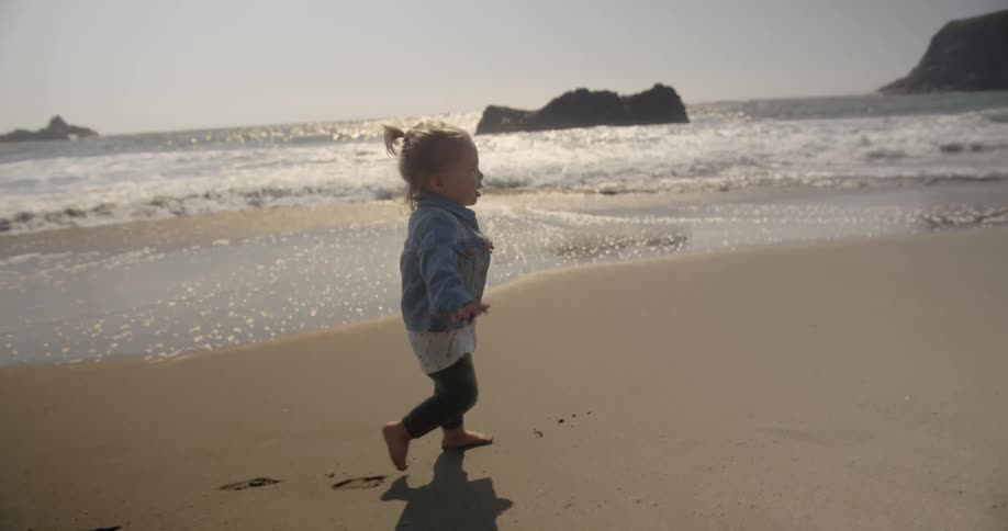 A young girl walks on the sand