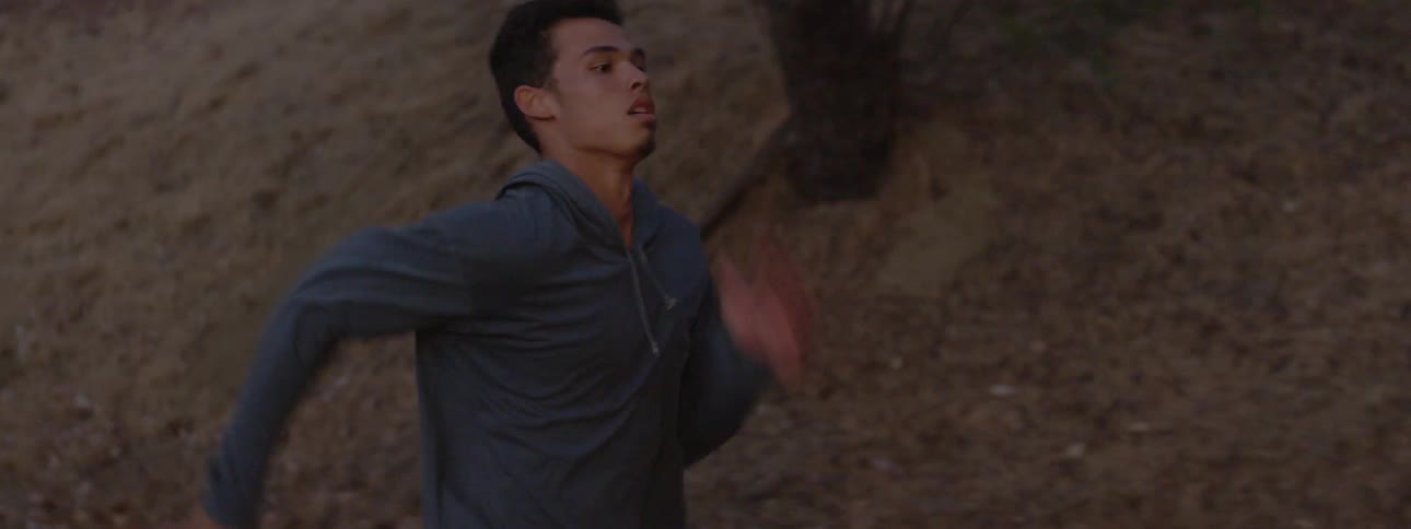 A man runs past a grassy hill