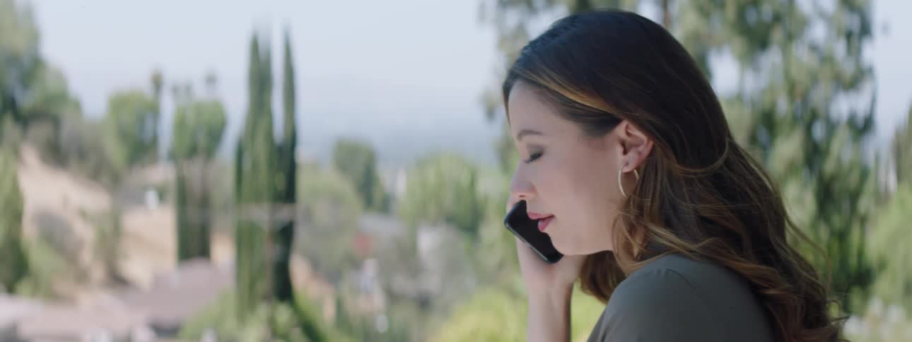 Woman talks on a phone while standing outside