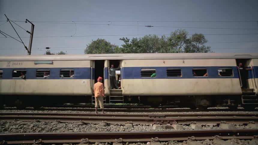 Trains passing by a woman who is standing on the tracks