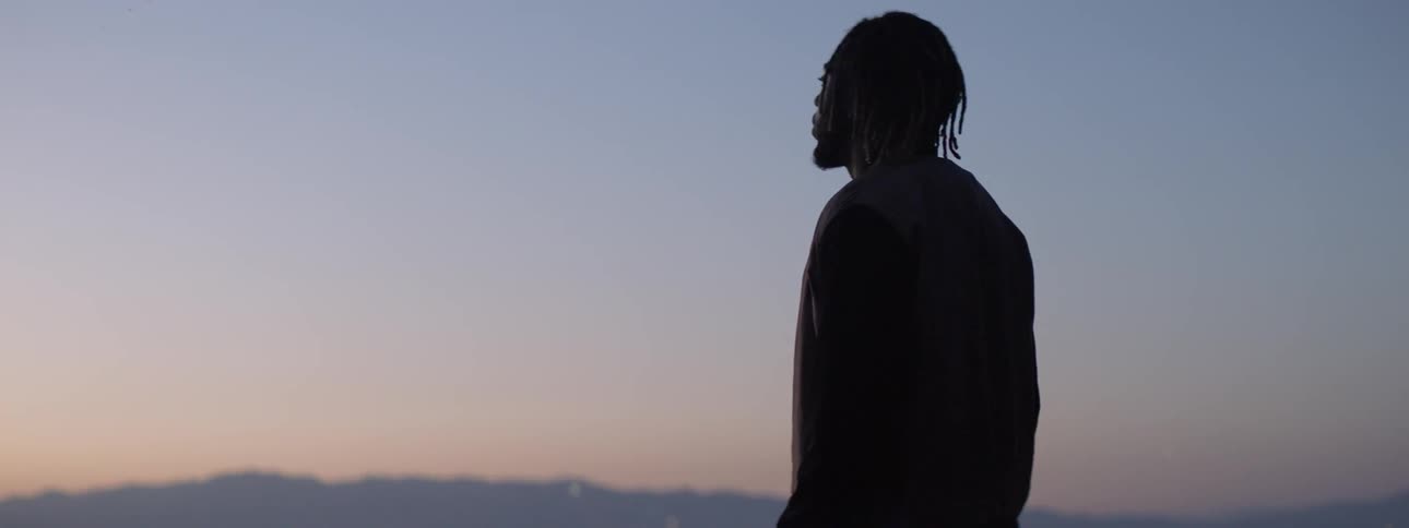 A man stands outside at sunset