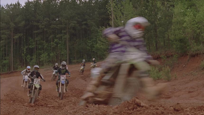 Racers ride dirt bikes on a muddy track