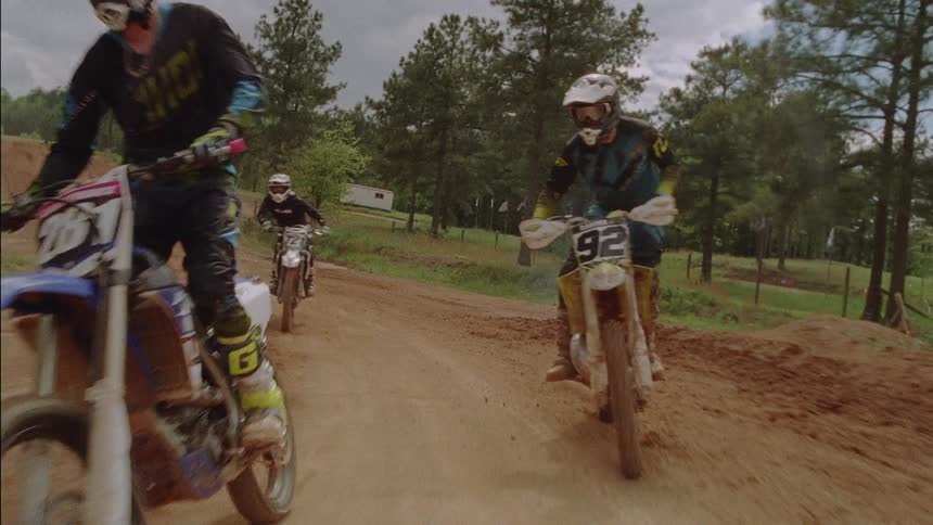 Dirt bikes are riding around a dirt track