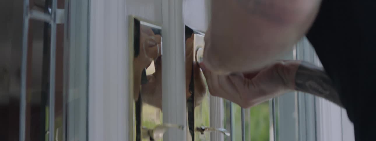 A man with a gun sneaks around a house and picks the lock