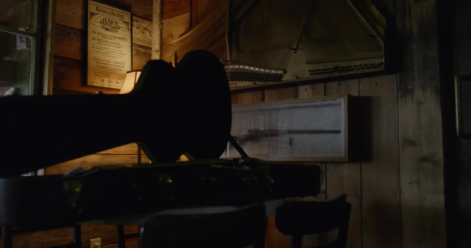 An open guitar case sits on a table in a room with a lamp on