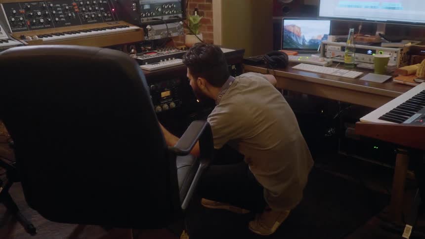 A man is crouched down in his studio operating a machine