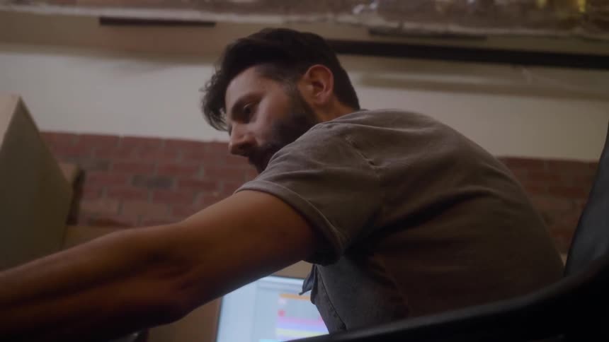A bearded man turns toward his computer