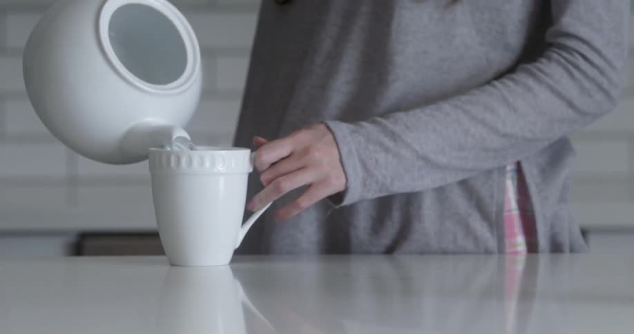Woman serving herself a cup of water from a teapot
