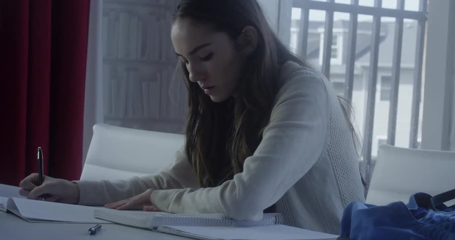 Woman sits at table and writes in notebook