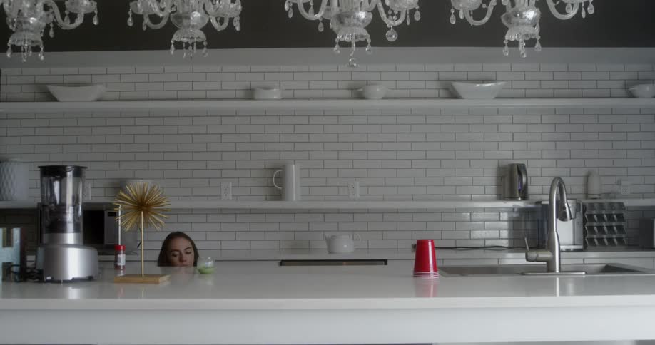 A woman looks in a cabinet in her kitchen