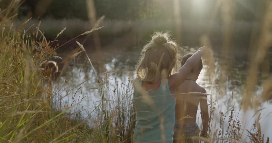 Children play at the edge of a pond