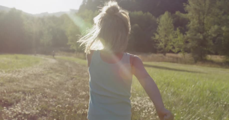 Little girl is running in the grass outside in the sunshine