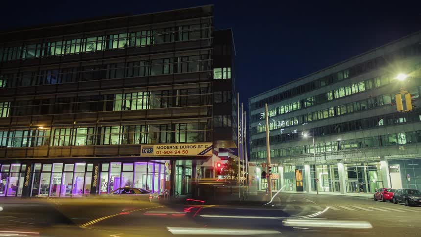 Cars drive through a city intersection at night