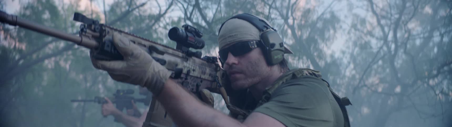 Soldiers walk while aiming rifles