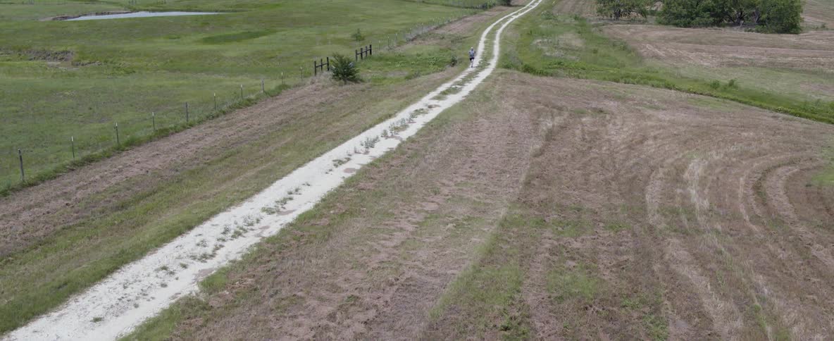 Someone is jogging down a dirt road