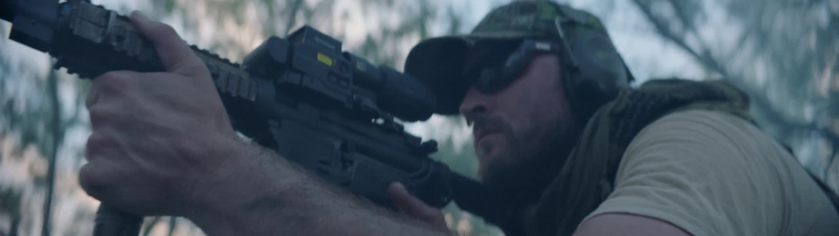 A soldier is looking through the scope of his gun
