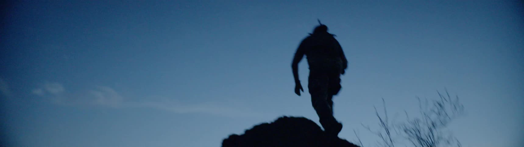 A soldier with a gun is climbing to the top of a rock overlook