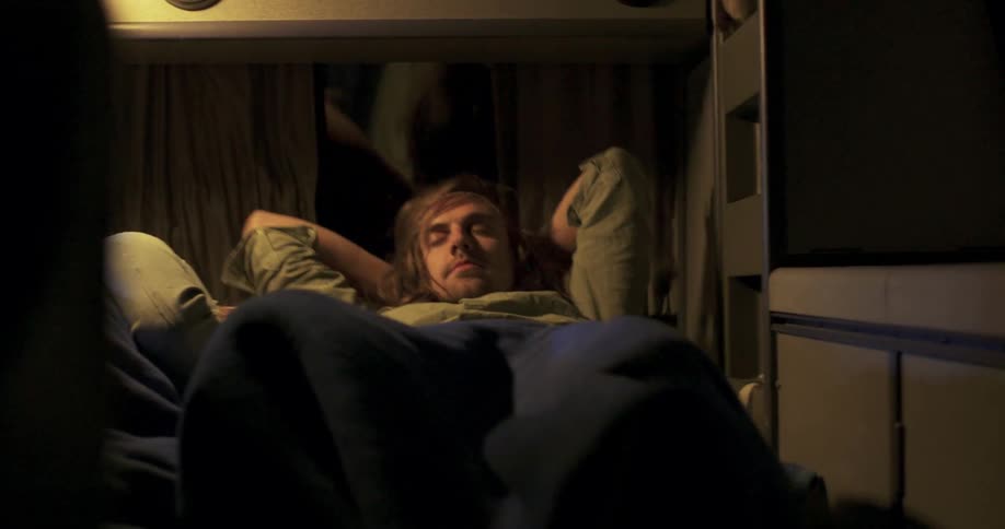 A man lays down in a bedroom cabin