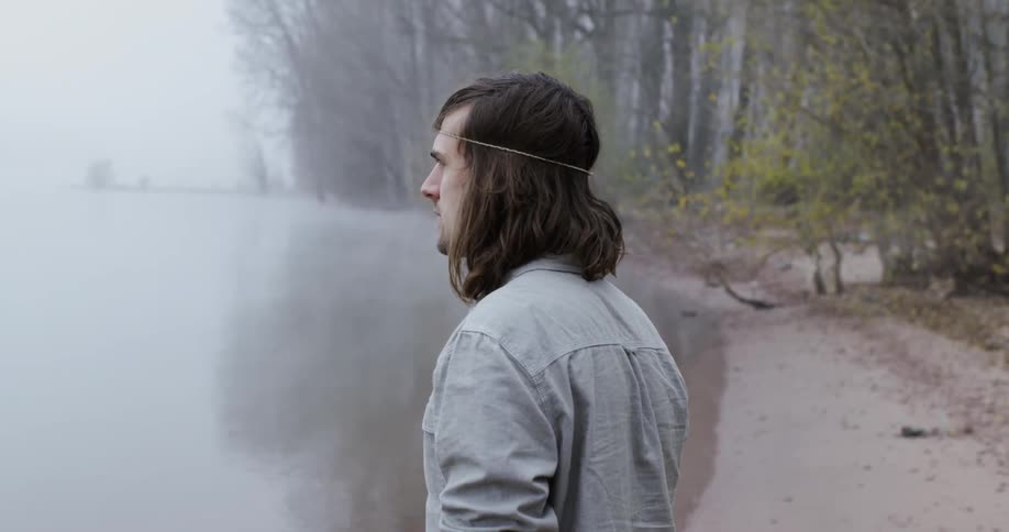 A man is looking out over the foggy waters