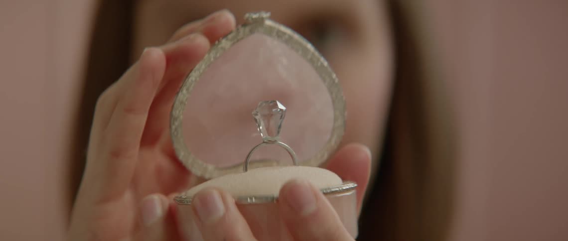 Woman holds up an open jewelry box with a diamond ring