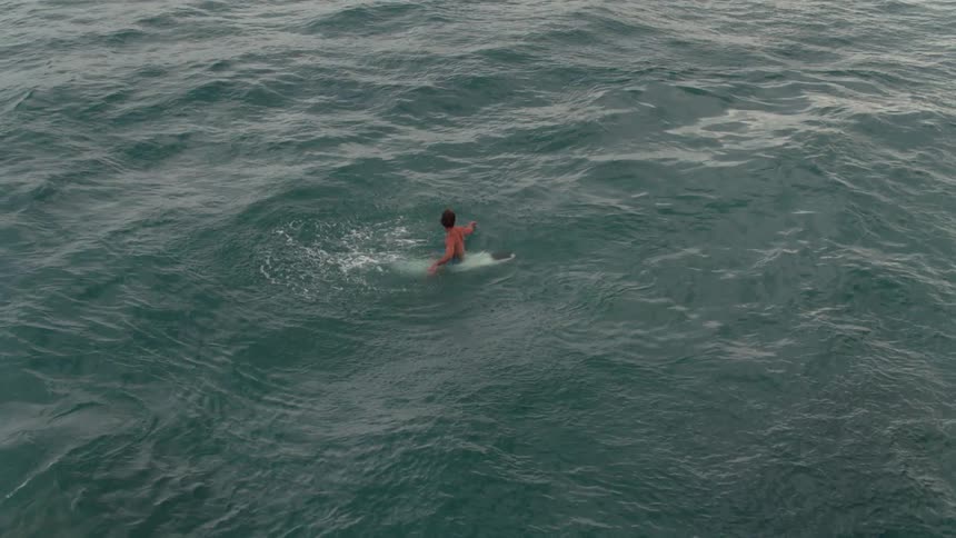 A surfer floats and splashes water