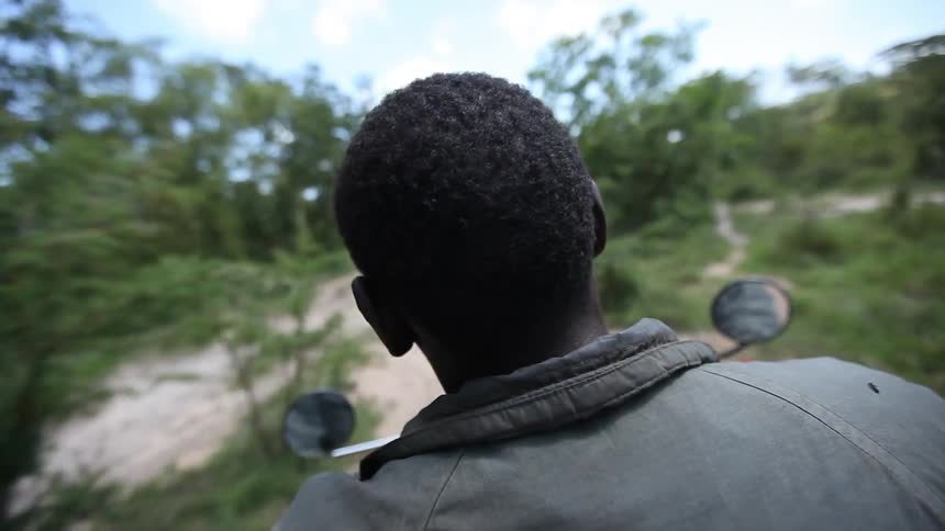Black man rides a motorcycle over a muddy road