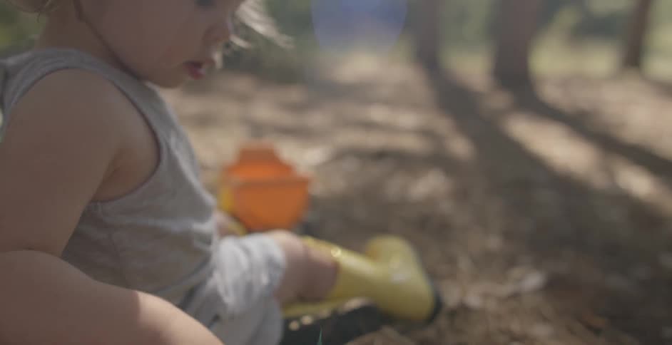 A child plays with toy tractors outside