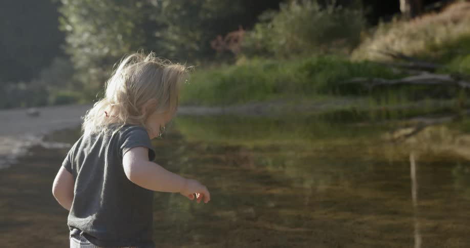 A toddler splashes in a stream