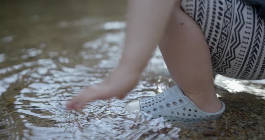 A child at the lake's edge splashes in the water
