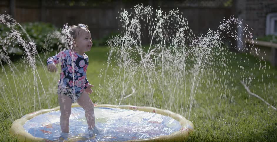 A child plays in the pool of water in the yard