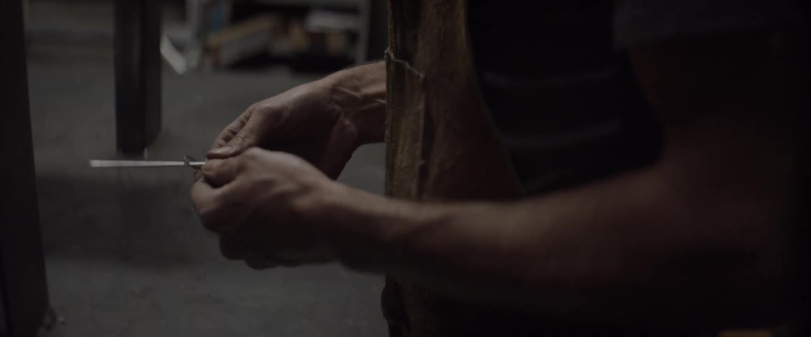 A man is looking down holding a piece of metal
