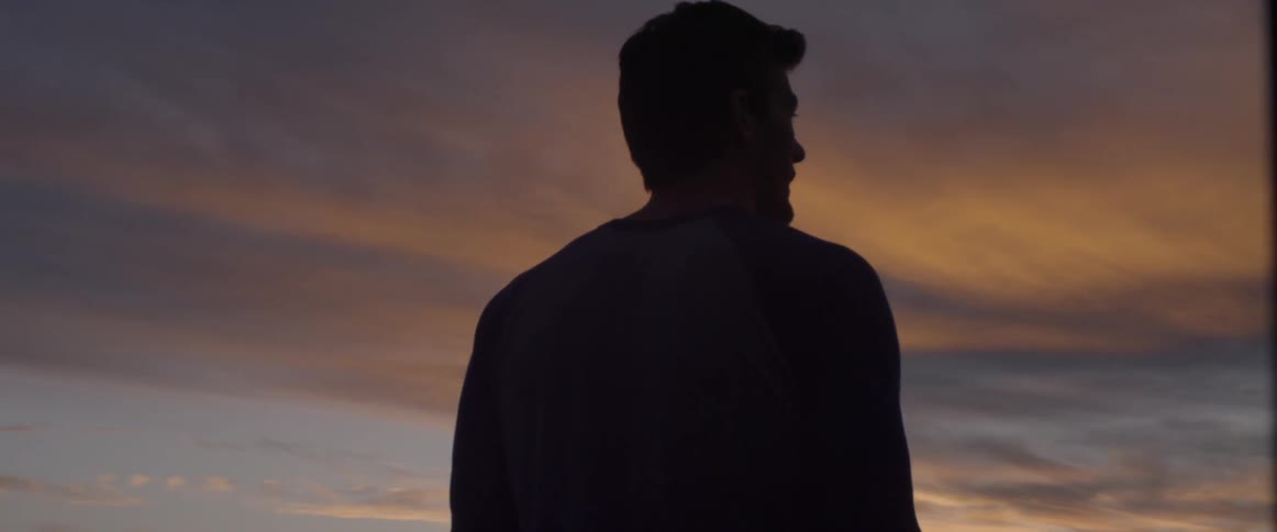 A man is looking out over the setting sun