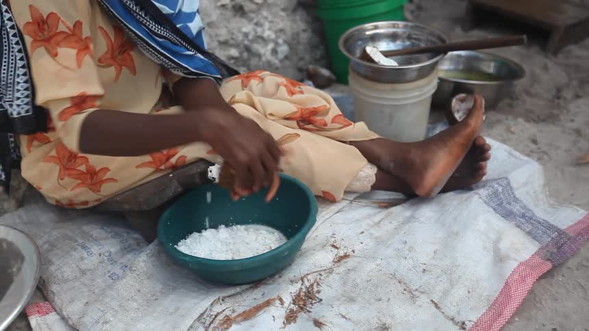 Woman shakes a container over a bowl of flour