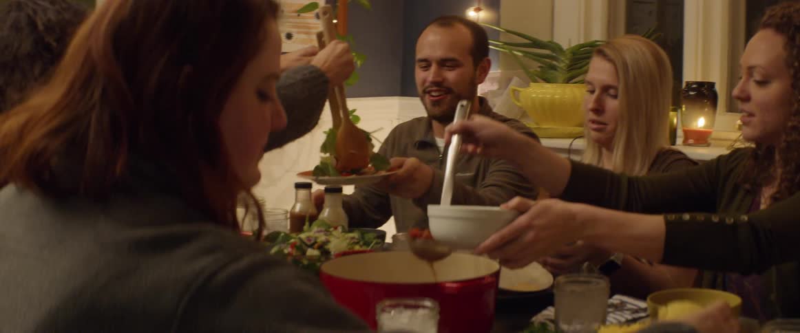 Friends sitting around a dinner table serve each other food