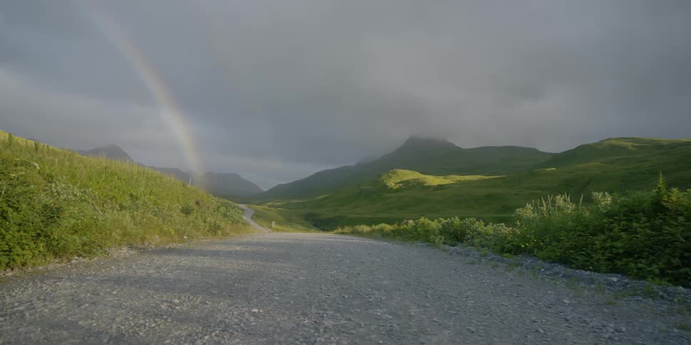 A rainbow stretches from the sky down to the road