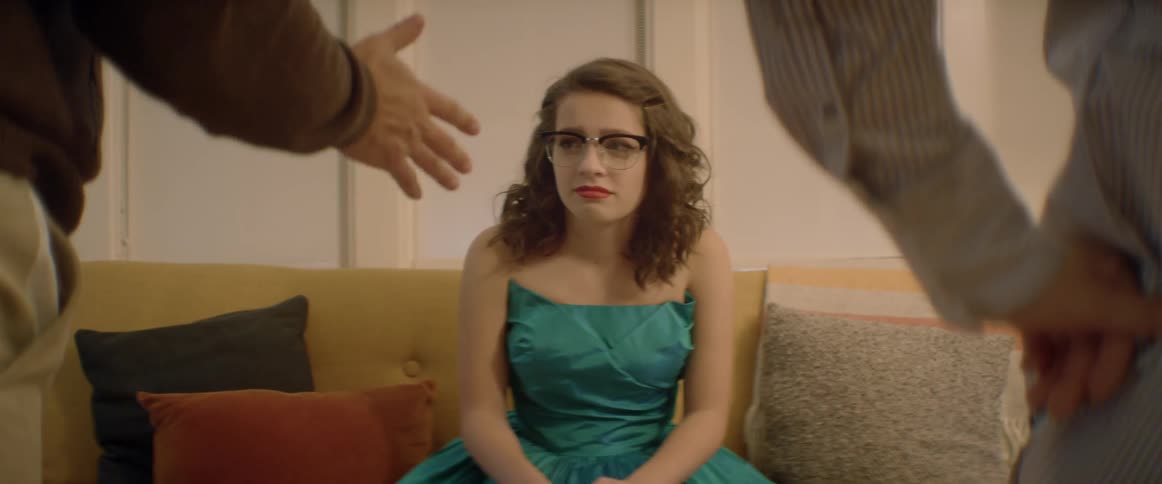 A teenage girl is cringing as her parents lecture her in a living room