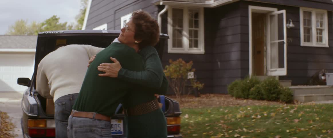 A mom hugs her son as his car is being loaded