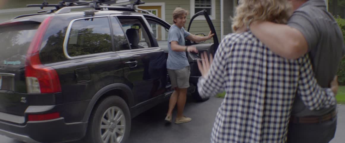 Parents watch their son get into a car