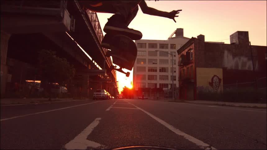 Man skateboards down the street at sunset