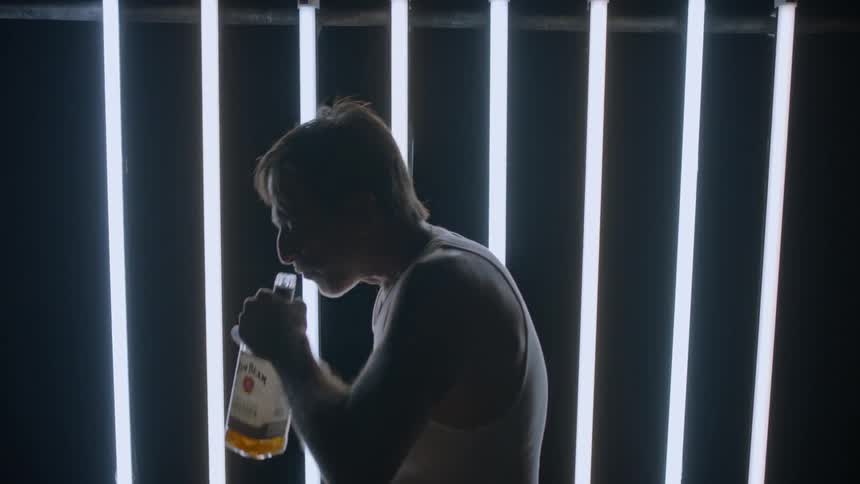 A man drinks from a whiskey bottle as he paces