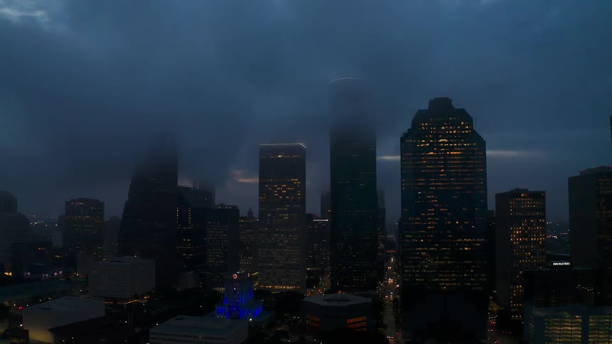 Tall city buildings tower into the foggy sky