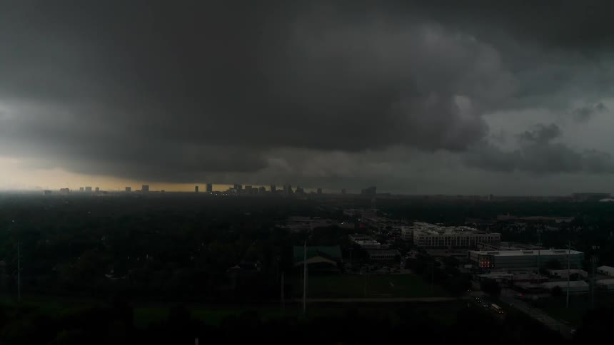 Storm clouds are moving across a city at dusk