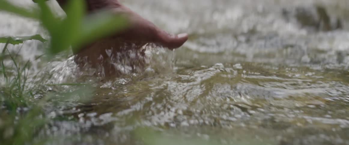 Person dips their hand in a shallow body of water